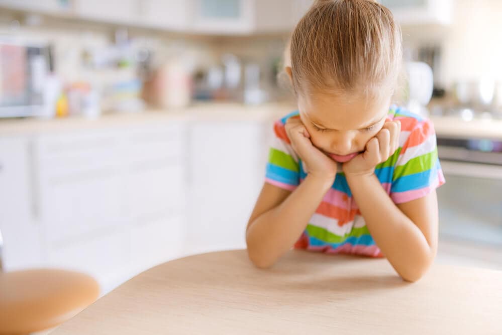Girl looking at the Table with Her Hands Holding Up Her Head