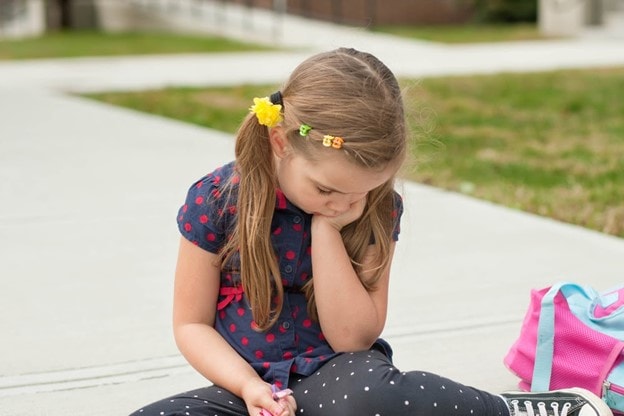 Young Girl Sitting on Ground Pouting Upset